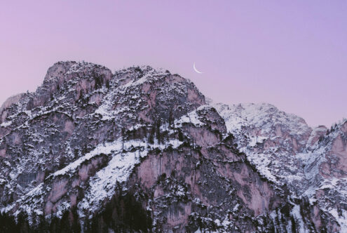Snow-covered mountain peaks at dusk with crescent moon, ideal for graphics, nature mockups, and mountain-themed design assets.
